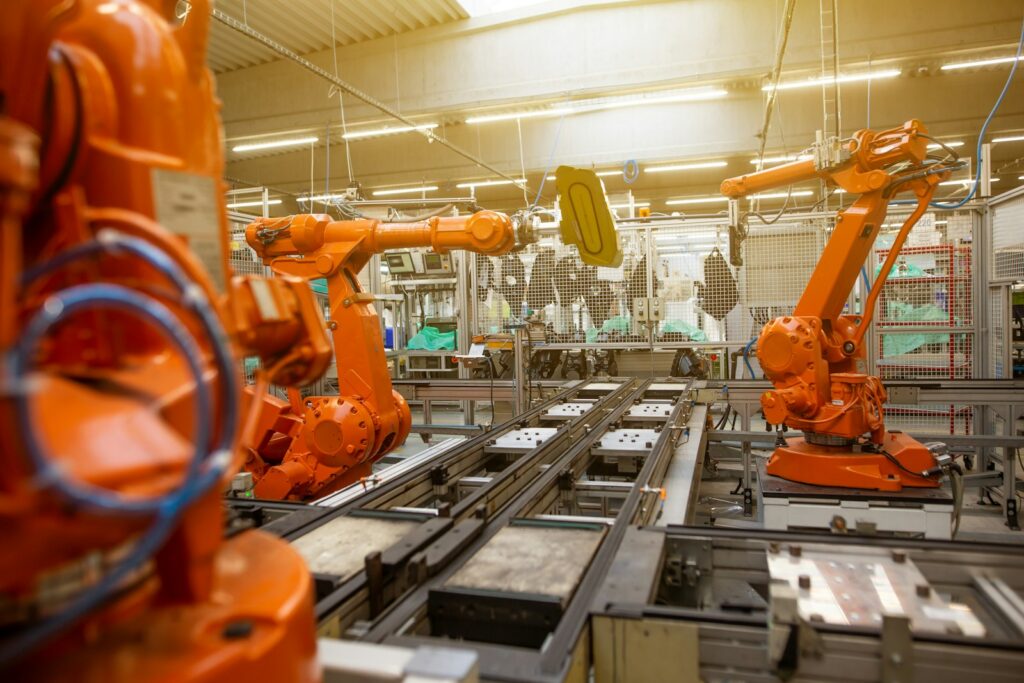 Pomarańczowe roboty przemysłowe na linii produkcyjnej